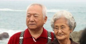 An elderly couple taking a photograph at the beach