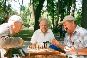 Three senior men sitting at a table and playing chess
