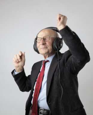A happy elderly man with earphones listening and dancing to music - Guide to Restless Legs Treatment Devices