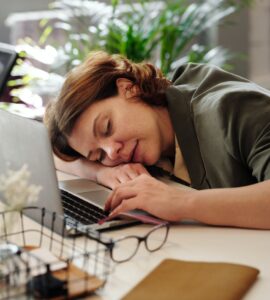 A Woman Who Has Fallen Asleep, Head Down on the Laptop at Her Desk