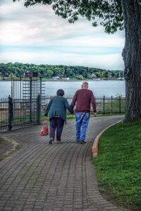 An elderly couple walk hand-in-hand along a 