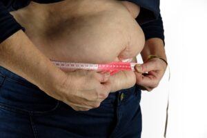 Obese Man Measuring Round His Abdomen With Measuring Tape
