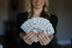 Woman holding money - 50 Savvy Saving Hacks For Seniors