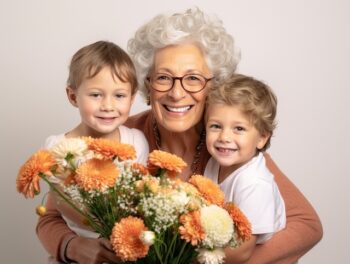 Smiling grandmother with glasses holding her two grandsons and flowers - Eye Health in Seniors