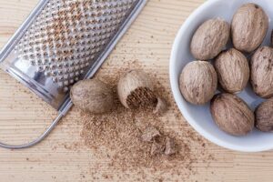 Nutmegs in a white bowl and a metallic grate and grated nutmeg beside the bowl - How to Boost Brain Power