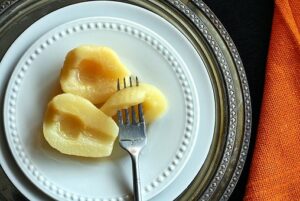 Canned pear removed from syrup on a plate with a spoon
