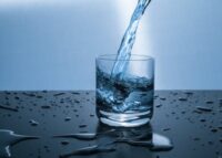 Water is being poured into a glass on a table -Why is Water Important to Your Health