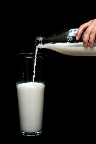 A Glass of Milk Being Poured from a Milk Bottle - Common Causes of Stomach Bloating