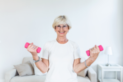 Senior exercising with two pink dumbbells