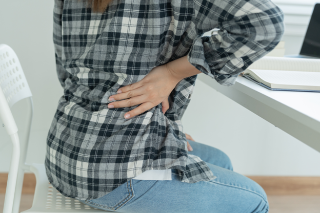 Woman suffering from back pain sitting down with hand pressing her back - Lower Back Pain in Seniors
