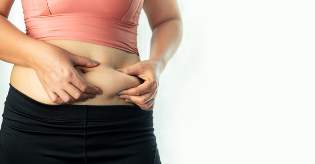 Woman pinching her belly fat with both hands - 5 Ways to Combat Middle Age Spread