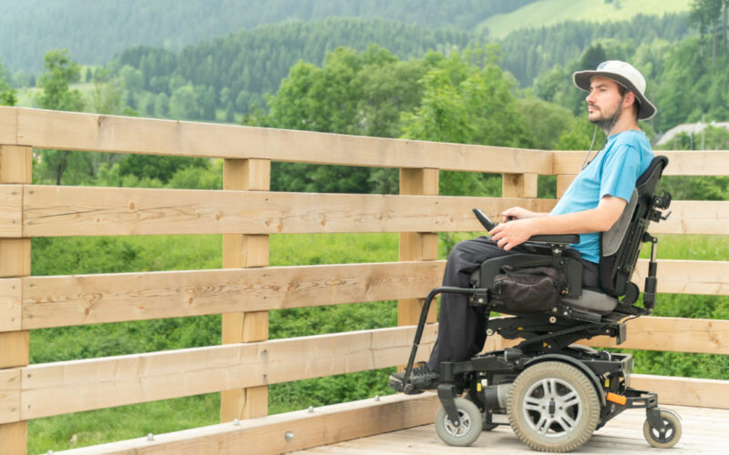 Man sitting on an electric wheelchair on a wooden deck - 9 Best Electric Wheelchairs with Recline Features for Seniors