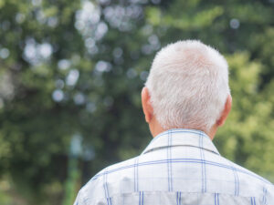 Back view of an elderly man with short gray hair while standing outdoors - Aging and Bladder Problems