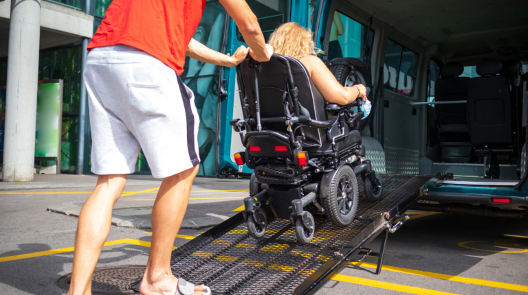 man pushing a woman on an electric wheelchair over portable ramp into van - Electric Wheelchair Assessories Buying Guide